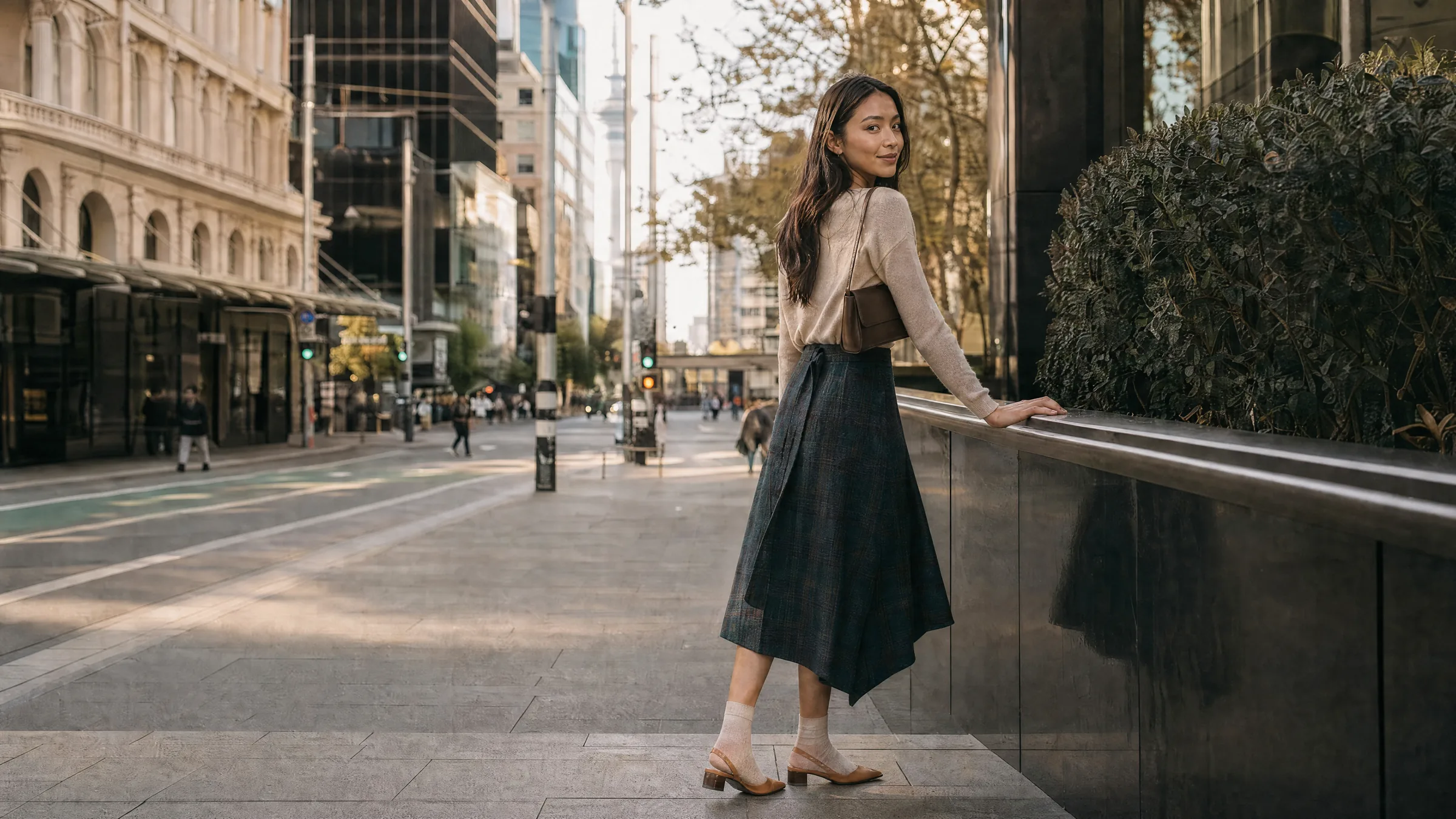 A student on an Auckland city street with the Sky Tower behind — Bada Global Study New Zealand